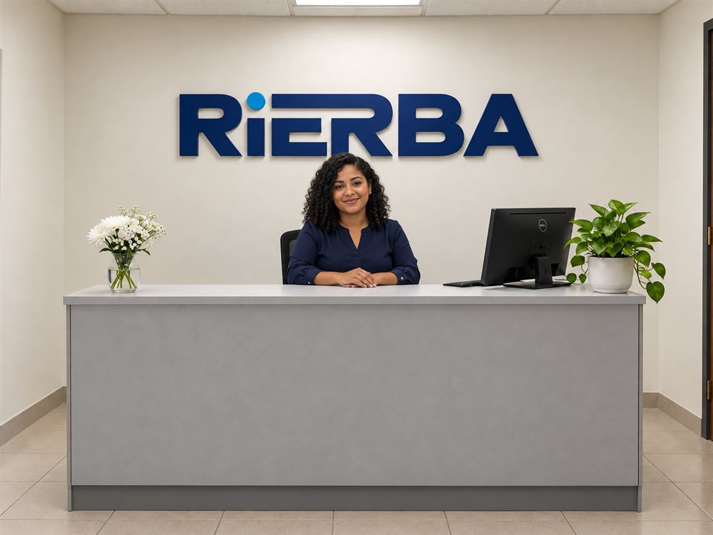 Imagen ilustrativa de una recepcionista en una recepción sencilla con letrero RIERBA y plantas